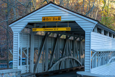 Information sign on bridge amidst trees and buildings