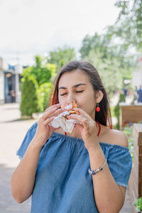 Portrait of young woman eating food at street