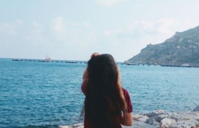 Rear view of woman looking at sea against sky