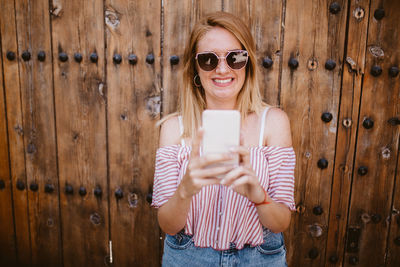 Blonde woman smiling and laughing as she looks at her cell phone