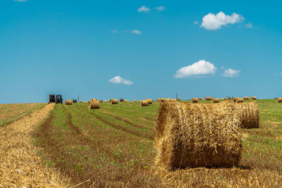 Hay bales on field against sky