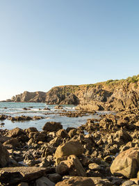 Rocks on beach against clear sky