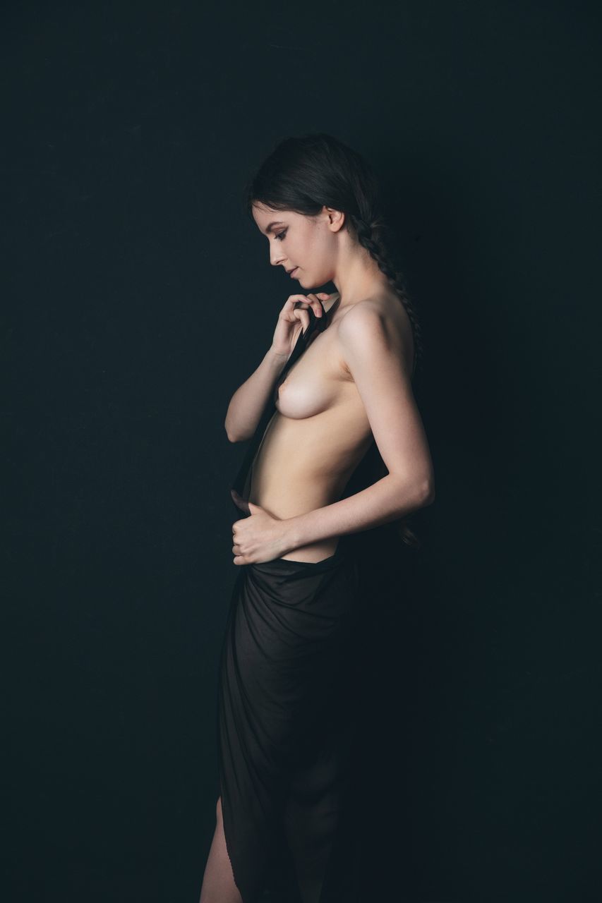 one person, studio shot, women, adult, young adult, indoors, black background, photo shoot, hairstyle, fashion, clothing, standing, portrait, three quarter length, long hair, female, dress, person, side view, black, copy space, elegance, brown hair, looking, hand, emotion, glamour, lifestyles, human leg