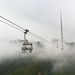 Overhead cable car over mountains against sky