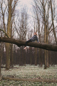 Graceful woman resting on fallen trunk over flowers scenic photography