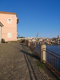 Buildings by river against clear blue sky