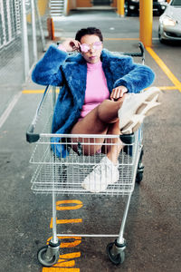 Full length of woman sitting in shopping cart