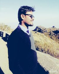 Young man standing on mountain against clear sky