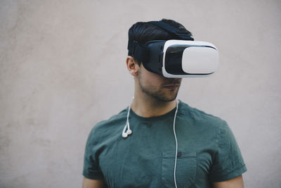 Computer programmer using vr glasses against beige wall in office