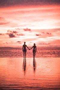 Silhouette men standing on beach against sky during sunset