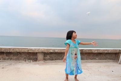 Full length of boy standing on beach against sky