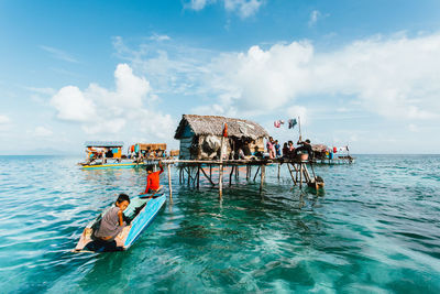 People on boat in sea against sky