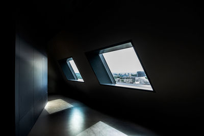 Dark room with window view over modern city