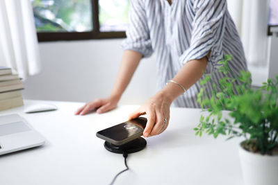 Midsection of man using mobile phone on table