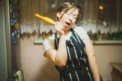 Woman making face while holding rolling pin