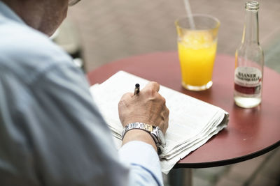 Senior man in a cafe writing on newspaper