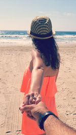 Midsection of woman on beach against sky