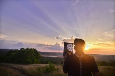 Man standing by plants against sky during sunset