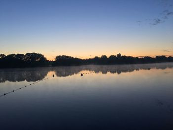 Scenic view of lake against clear sky at sunset