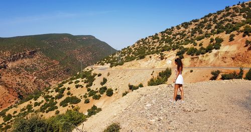Rear view of woman standing on mountain against sky