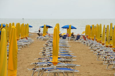 Hooded chairs on beach against sky