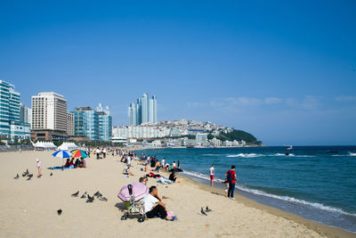 People at beach against clear blue sky