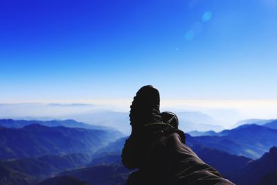 Low section of woman on snowcapped mountain against sky