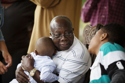 Senior man embracing boy while talking with grandson at porch