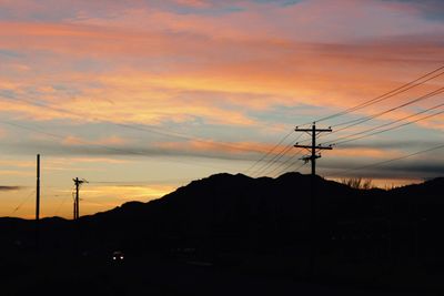 Silhouette electricity pylon against sky during sunset