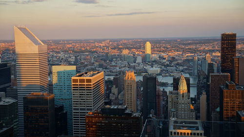 Aerial view of illuminated buildings in city against sky during sunset