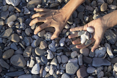 Woman hands touching stones on the beach. grey stones