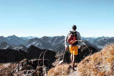 Rear view of man looking at mountains against clear sky