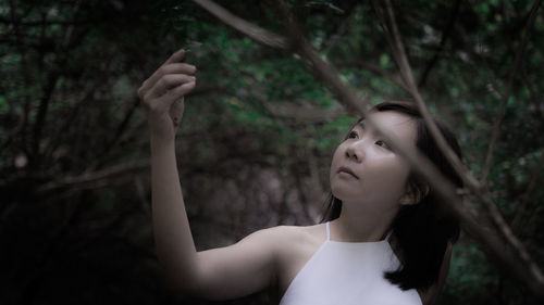 Portrait of woman looking away while sitting on tree