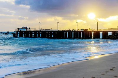 Pier over sea against sky during sunset