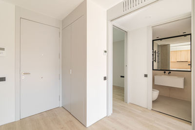 Entrance to the interior of modern apartment with white walls and wooden floor. 