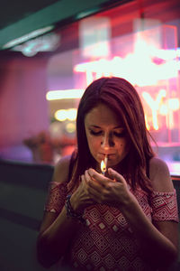 Young woman looking at illuminated camera