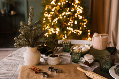 Christmas decor on the background of lights. christmas tree branches in a vase, rolling pin