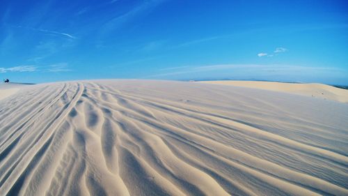 Scenic view of sand dunes against blue sky