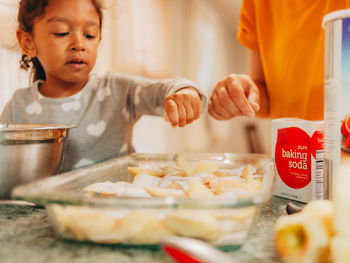 Mother at home preparing apple crisp with her young daughter