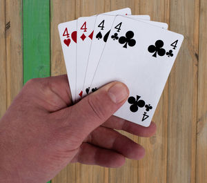 Cropped hand holding cards at wooden table