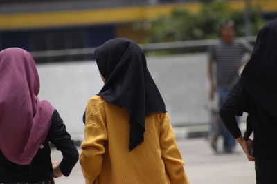 Rear view of people walking on street in city