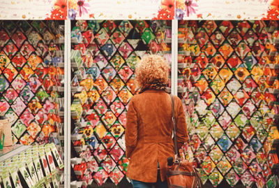 Rear view of woman looking at flower seed packets at market