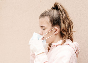 One blonde girl wearing latex gloves and face masks is showing the way she protects herself from coronavirus, bacterias, virus, fungus, etc. she removed mask to take clear breath. horizontal