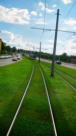 Road on grassy field against cloudy sky