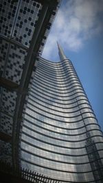 Low angle view of skyscrapers against cloudy sky