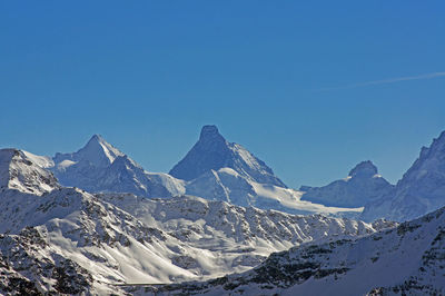 Scenic view of snow covered mountains against blue sky