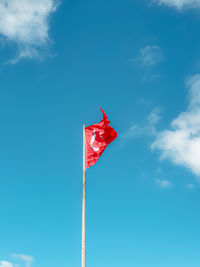 Low angle view of flag on pole against blue sky