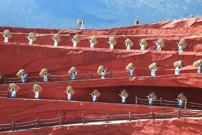 Low angle view of women with wicker baskets walking on road against mountain