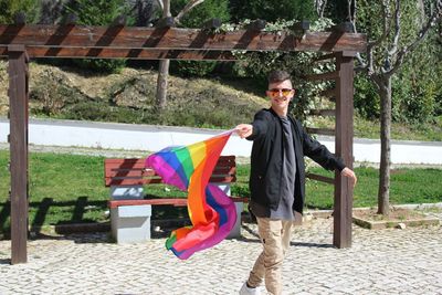 Full length of a smiling man holding rainbow flag
