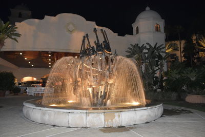 Illuminated fountain against building at night